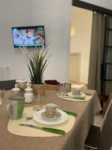 玛格丽塔萨沃亚Maioliche Apartments的一张桌子,桌子上放有盘子和杯子,房间里还有一台电视机