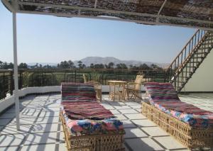 Jazīrat al ‘AwwāmīyahNile Paradise的庭院设有两张柳条床,配有桌椅