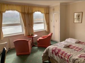 洛哈尔什教区凯尔高地Lochalsh Hotel with Views to the beautiful Isle of Skye的一间卧室配有两把椅子、一张床和两个窗户。