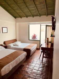 通哈Hotel Posada de San Agustin的一间卧室设有两张床、一张桌子和一个窗口。