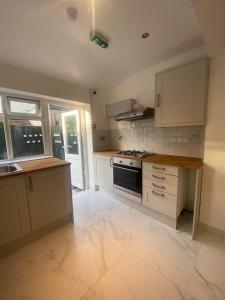 伦敦Cosy house in Newham的厨房配有白色橱柜和炉灶烤箱。