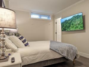 温哥华Nice home away at Vancouver near YVR的卧室配有一张床,墙上配有电视。
