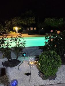尼姆jolie Mazet avec piscine privée !的夜间游泳池,有树木和灯光