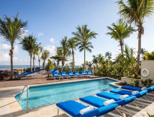 圣胡安康达多范德比尔特酒店的一个带蓝色躺椅的游泳池,棕榈树