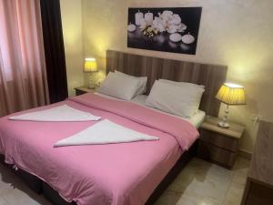 安曼Suzan Hotel Apartments的卧室配有粉红色的床和2个枕头