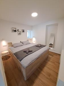 木洛希尼Apartman Tea的白色客房的一张大床,铺有木地板