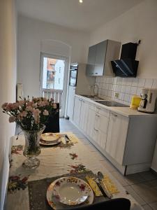 阿尔滕堡Käthe-Kollwitz-Straße 54, F2的厨房配有带盘子和鲜花的桌子