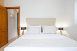奈德里Adria Luxury Apartments的一间卧室配有一张带两盏灯的大型白色床。