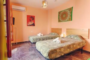 内尔哈Charming Nerja Hostel的橙色墙壁客房的两张床