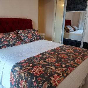 克里西玛Espaço aconchegante em Criciúma的一间卧室配有一张带鲜花毯子和镜子的床