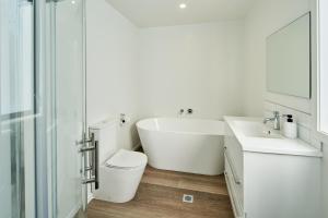 惠灵顿Brand New with Ocean Views的带浴缸、卫生间和盥洗盆的浴室