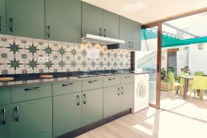 内尔哈Charming Nerja Hostel的厨房配有绿色橱柜、洗衣机和烘干机