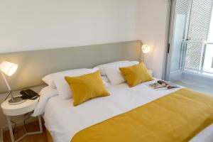 蒙得维的亚梅里特蒙得维套房公寓的一间卧室配有黄色和白色枕头的床