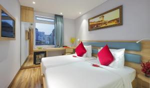 胡志明市RAMADA ENCORE BY WYNDHAM SAIGON D1 - Formerly M Boutique Hotel Saigon的卧室配有带红色枕头的大型白色床