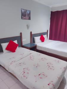 MukahHighway Inn的客房内的两张床和红色枕头