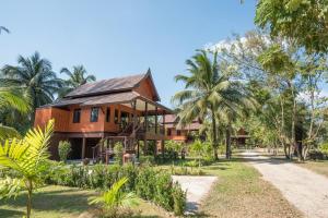 蔻立ThaiLife Wellness & Meditation Resort- SHA Plus的前面有棕榈树的房子
