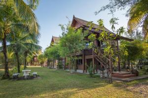 蔻立ThaiLife Wellness & Meditation Resort- SHA Plus的一个带长椅和棕榈树的院子的房子