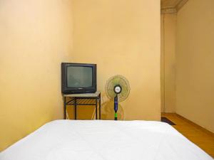 名古屋SPOT ON 92569 Anto Homestay Syariah的一间卧室配有一张床、一台电视和风扇