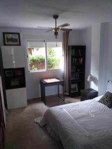 卡萨雷斯Planta baja cerca de la playa Casares Costa的一间卧室配有一张床、一张桌子和一个窗户。