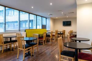 利物浦Heeton Concept Hotel - City Centre Liverpool的餐厅设有桌椅和窗户。
