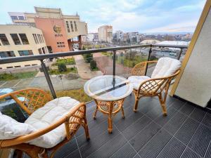 克卢日-纳波卡Red Hotel Riviera Suite&Lake的阳台配有椅子和玻璃桌。