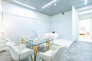 广岛Randor Hotel Hiroshima Prestige的一间设有玻璃桌和白色椅子的用餐室