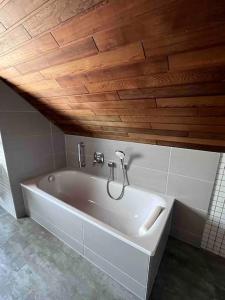 格罗尔斯泰因Gasthaus Maarfeld Gerolstein的浴室设有白色浴缸,拥有木制天花板