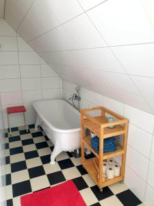 斯塔德Egen ovanvåning i charmig villa nära havet的带浴缸的浴室,铺有 ⁇ 格地板
