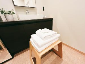 GotsuFELIZ ARIFUKU ONSEN的浴室凳子上堆着的毛巾