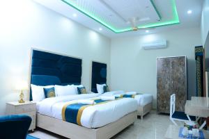 拉合尔GO Luxury Grand Hotel的一间卧室设有两张床和蓝色的墙壁