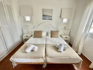 苏昂博Ca Mestral Son Bou Urbanización típica menorquina.的白色卧室配有两张带毛巾的床