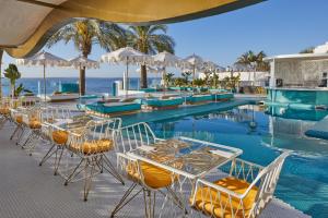 普拉亚登博萨Dorado Ibiza - Adults Only的毗邻大海的带桌椅的游泳池