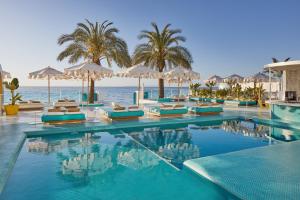 普拉亚登博萨Dorado Ibiza - Adults Only的一个带椅子和遮阳伞的游泳池以及大海