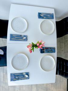 里耶卡Luxury Apartman ASIA Rijeka的一张白色的桌子,上面有四个盘子和鲜花