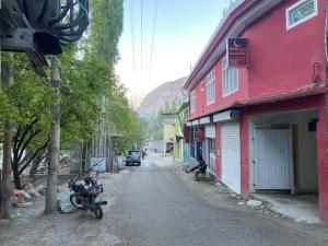 KhapaluMoon Light Guest House Khaplu的一条有红色建筑和摩托车停在路边的街道