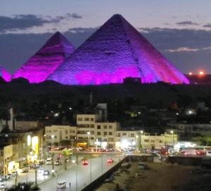 开罗king ramses pyramids view apartment的享有金字塔的夜间美景,配有紫色灯光