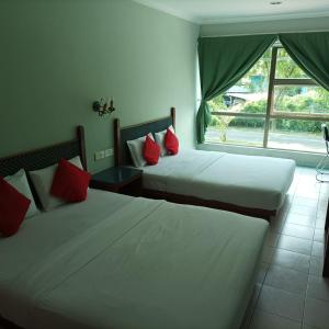 MukahHighway Inn的带窗户的客房内的两张床和红色枕头