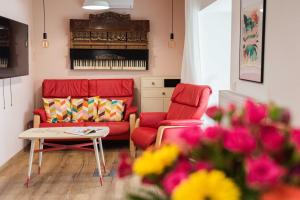许迈格Bökény-vendégház的客厅配有2把红色椅子和桌子