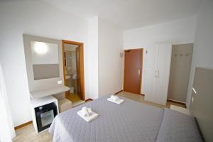 里米尼伊斯基亚酒店的一间卧室配有一张带两条白色毛巾的床