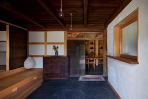 AkaiwaCasa KitsuneAna The Satoyama experience in a Japanese-style modernized 100-year-old farmhouse的一间设有木制天花板的客房和一间带桌子的客房