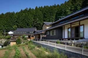 AkaiwaCasa KitsuneAna The Satoyama experience in a Japanese-style modernized 100-year-old farmhouse的森林旁的路上一排房子