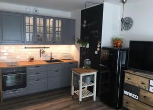 辛安诺泽蒂Apartament 5 mórz的厨房配有蓝色橱柜和黑色冰箱。