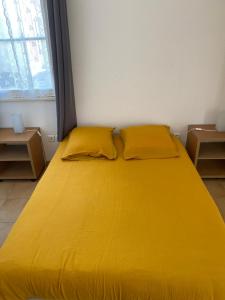 滨海苏拉克Appartement familial centre et plage的窗户客房内一张黄色的大床