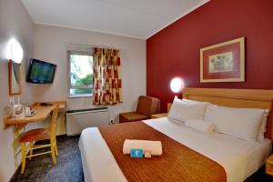 约翰内斯堡Road Lodge JNB Airport的酒店客房设有一张大床和一张书桌。
