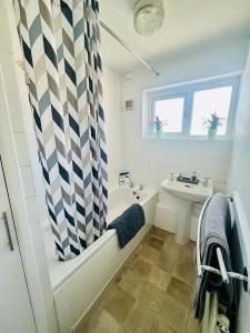 曼彻斯特Barnstaple Drive House的浴室配有淋浴帘、浴缸和盥洗盆。