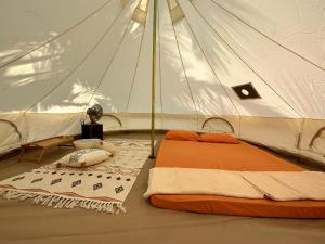 马六甲Beach N Breeze Glamping的白色帐篷内的一张床位,帐篷内配有一张桌子