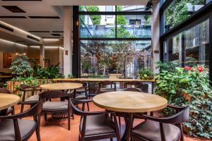 第比利斯第比利斯伊奥塔酒店的一间设有桌椅的餐厅,种植了植物