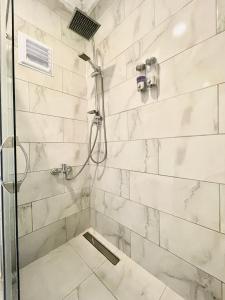 达拉曼Airport Guest House的一间设有白色大理石墙壁和淋浴的浴室