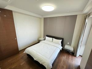 西归浦市Seopjikoji Oceanview Apartment的一间卧室配有带白色床单和枕头的床。
