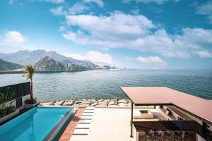 富查伊拉Luxury Villa 8 BR Sea and Mountain View with infinity pool - Al Dana Island Fujairah by OCEANVIEW HOLIDAY HOMES的水体旁边的游泳池